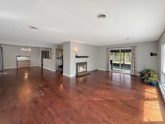 unfurnished living room with a chandelier, dark hardwood / wood-style flooring, and a baseboard heating unit