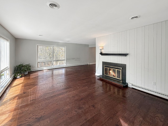 unfurnished living room featuring a baseboard heating unit, dark hardwood / wood-style flooring, and wooden walls