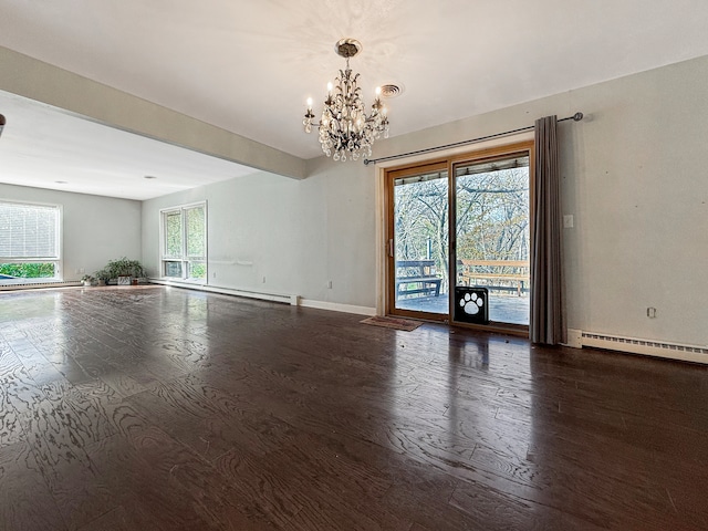 spare room with a chandelier, dark hardwood / wood-style floors, baseboard heating, and a healthy amount of sunlight