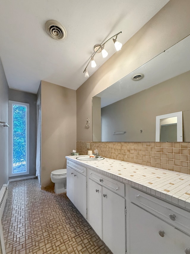 bathroom with tasteful backsplash, vanity, and toilet