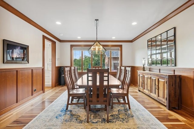 dining room with ornamental molding and light hardwood / wood-style flooring