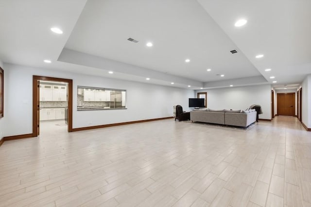 living room with light wood-type flooring and a tray ceiling