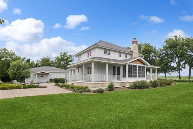 back of property with covered porch, a garage, and a lawn