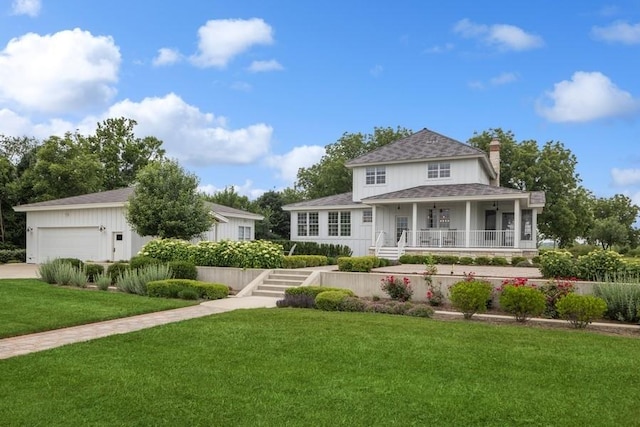 rear view of property featuring a lawn, a garage, and covered porch