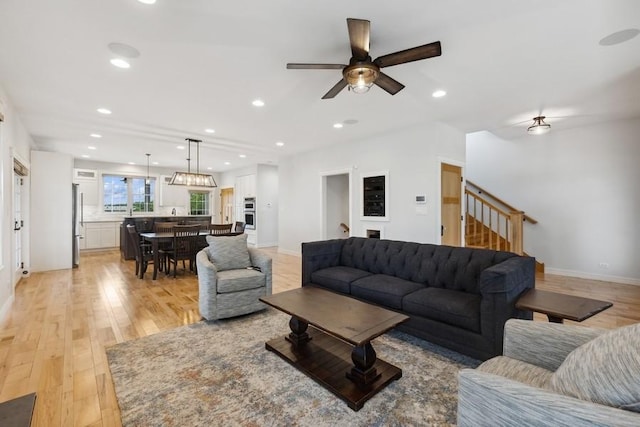 living room with ceiling fan and light hardwood / wood-style flooring