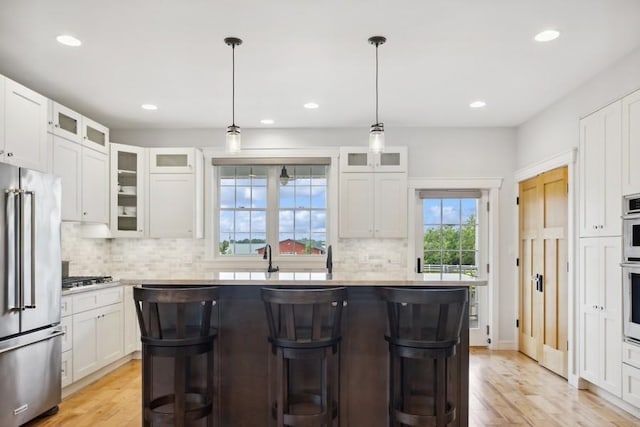 kitchen featuring white cabinets, stainless steel appliances, a kitchen island, and hanging light fixtures