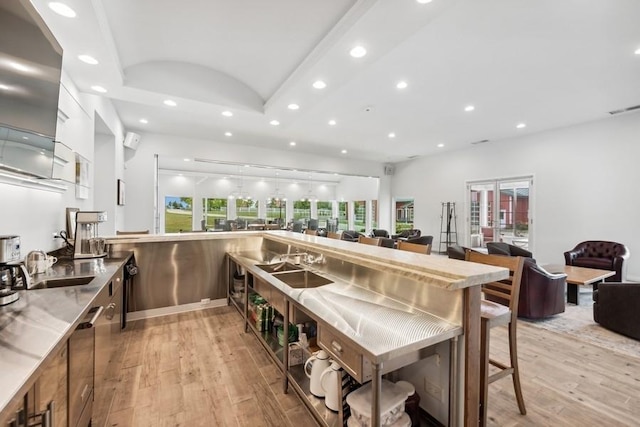 kitchen with a kitchen bar, sink, and light hardwood / wood-style floors