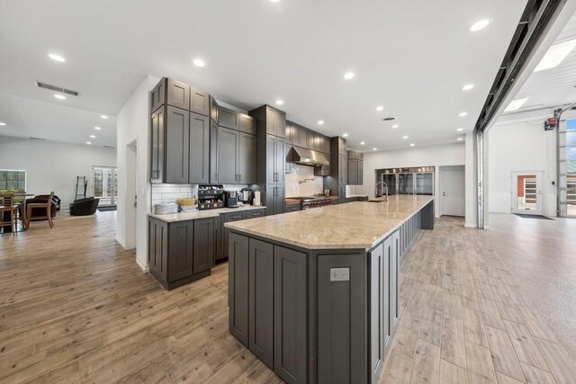 kitchen featuring light wood-type flooring, gray cabinets, extractor fan, and a spacious island