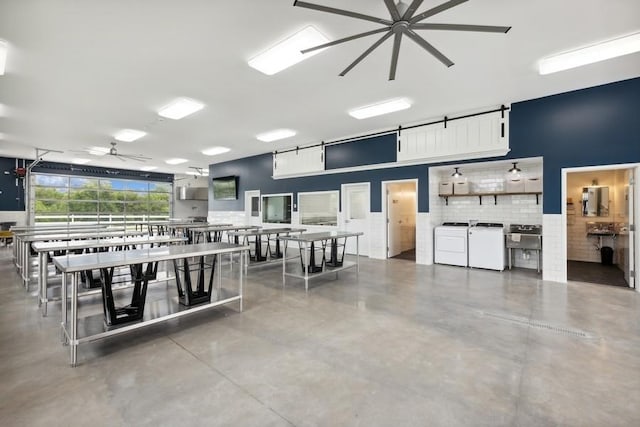 dining space featuring ceiling fan, independent washer and dryer, and concrete floors