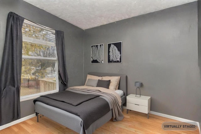 bedroom featuring a textured ceiling, multiple windows, and light hardwood / wood-style flooring