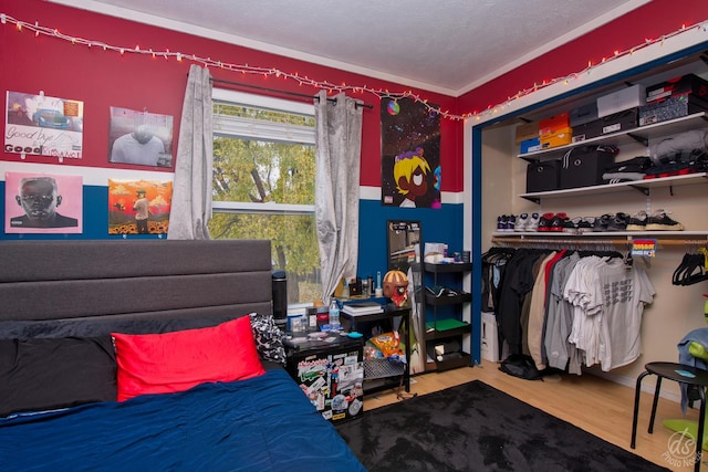 bedroom with hardwood / wood-style floors, a textured ceiling, and ornamental molding