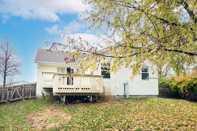 rear view of house featuring a lawn and a deck