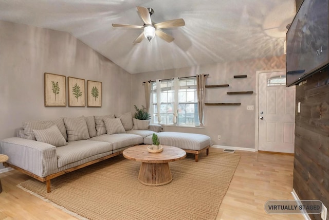 living room with ceiling fan, vaulted ceiling, and light hardwood / wood-style flooring