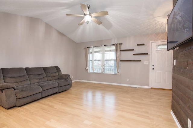 living room with ceiling fan, light hardwood / wood-style floors, and vaulted ceiling