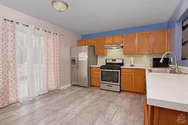 kitchen featuring light wood-type flooring, stainless steel appliances, tasteful backsplash, and sink