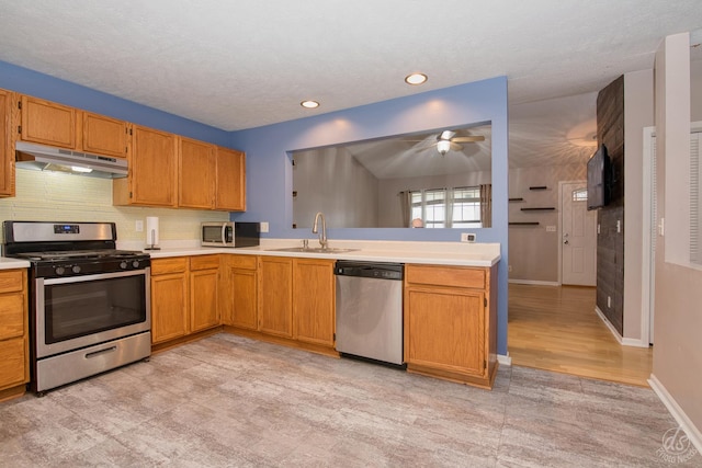 kitchen featuring ceiling fan, sink, kitchen peninsula, a textured ceiling, and appliances with stainless steel finishes