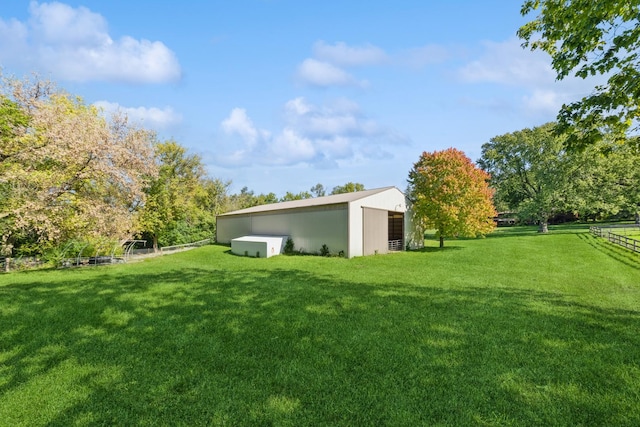 view of yard with a pole building, fence, a detached garage, and an outdoor structure