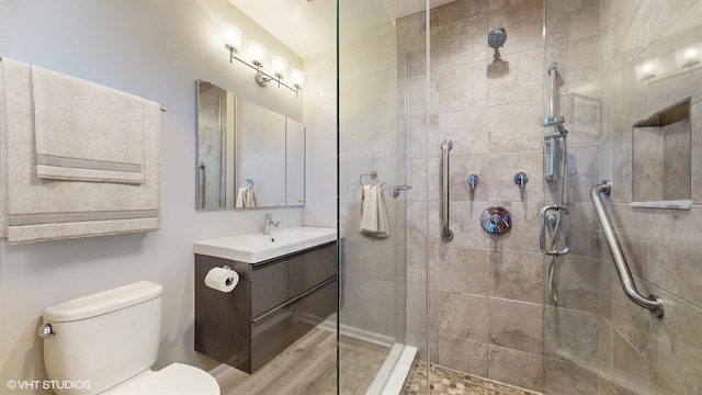 bathroom with tiled shower, vanity, and toilet