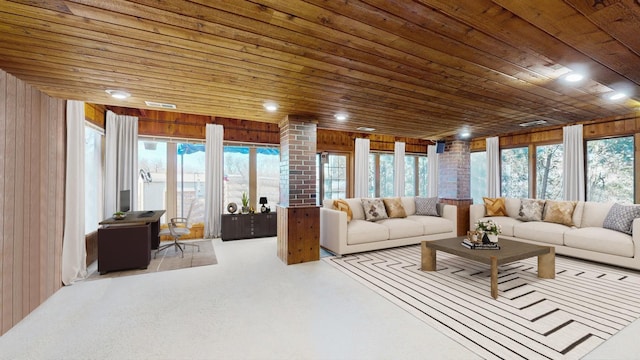 living area featuring plenty of natural light, wooden ceiling, decorative columns, and wooden walls