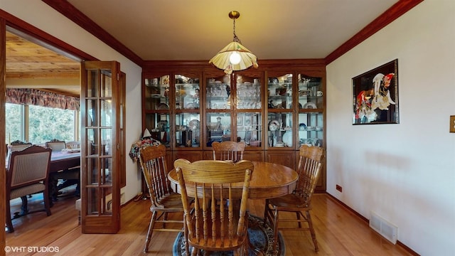 dining space with ornamental molding, visible vents, baseboards, and wood finished floors