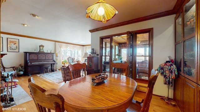 dining room featuring crown molding, baseboards, and light wood-style floors