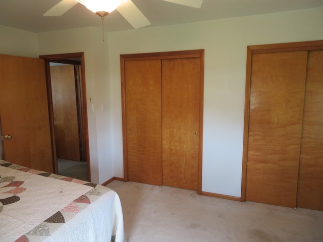 carpeted bedroom featuring ceiling fan and two closets