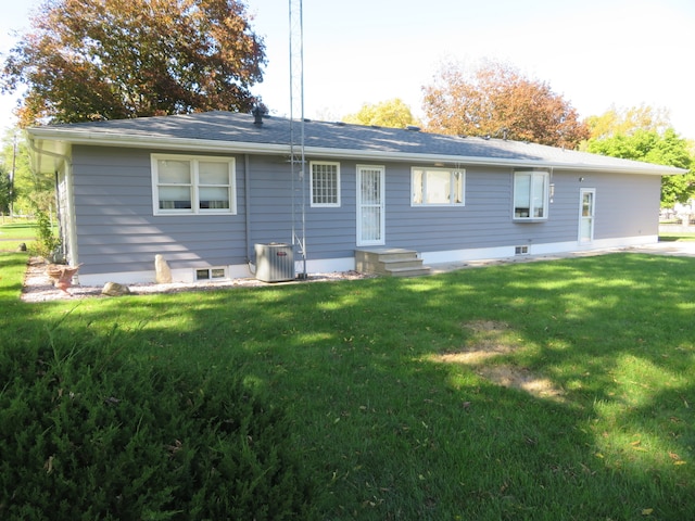 back of property featuring central AC unit and a yard