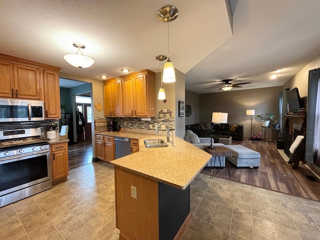 kitchen with kitchen peninsula, backsplash, sink, appliances with stainless steel finishes, and light hardwood / wood-style floors