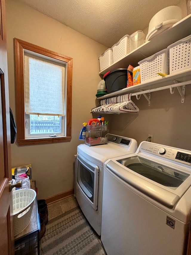 clothes washing area with independent washer and dryer, a textured ceiling, and dark tile patterned floors