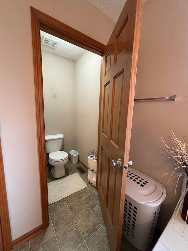 bathroom with tile patterned floors, a textured ceiling, and toilet