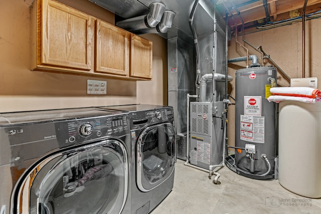 clothes washing area featuring washing machine and dryer, water heater, and cabinets