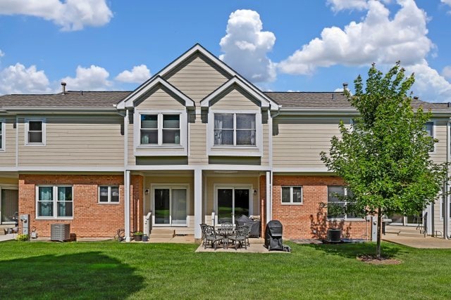 back of property with a lawn, a patio, and central AC