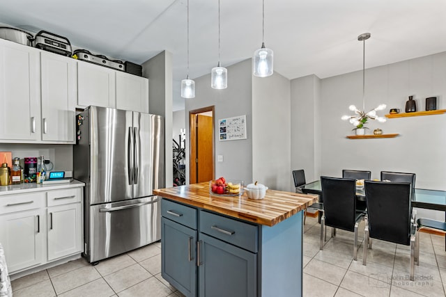 kitchen featuring stainless steel refrigerator, white cabinetry, an inviting chandelier, wooden counters, and pendant lighting