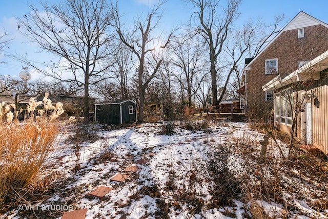 yard covered in snow featuring a storage shed