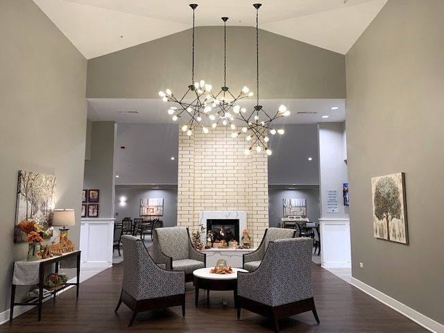 living room with a chandelier, high vaulted ceiling, dark wood-type flooring, and a brick fireplace