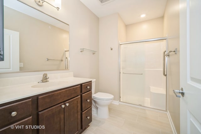 bathroom featuring vanity, an enclosed shower, and toilet