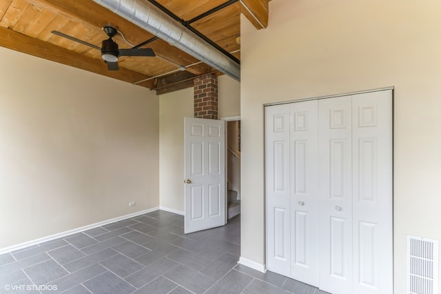 unfurnished bedroom featuring beam ceiling, wood ceiling, a closet, and ceiling fan