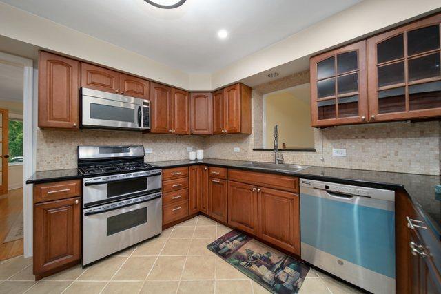 kitchen with dark countertops, stainless steel appliances, tasteful backsplash, and a sink