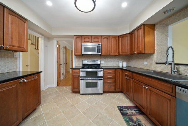 kitchen featuring a sink, tasteful backsplash, appliances with stainless steel finishes, and brown cabinetry