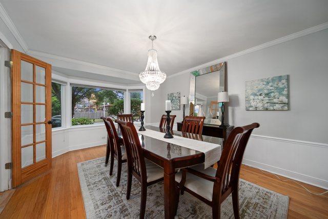 dining room with a notable chandelier, wainscoting, crown molding, and wood finished floors