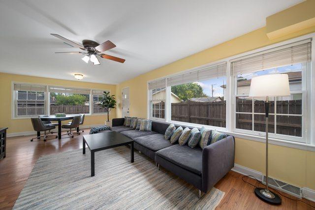 living room featuring a wealth of natural light, baseboards, wood finished floors, and a ceiling fan