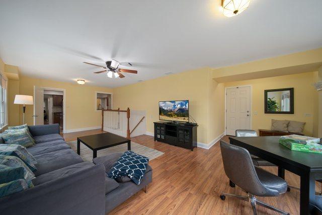 living room with baseboards, a ceiling fan, and light wood finished floors