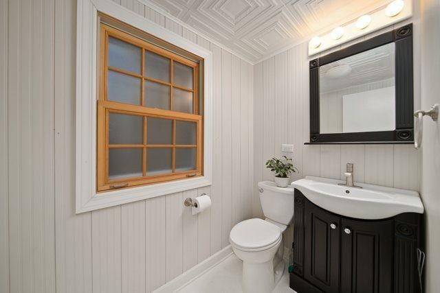 half bath featuring vanity, toilet, and an ornate ceiling