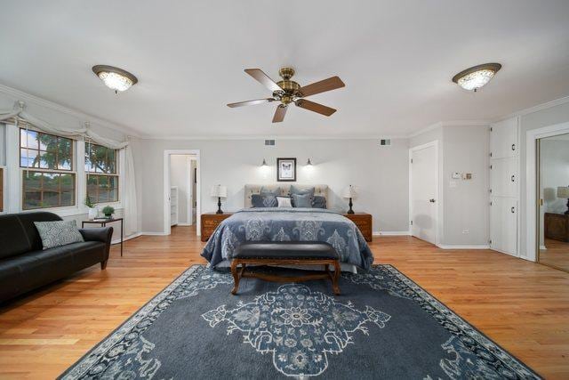 bedroom with visible vents, crown molding, baseboards, and wood finished floors