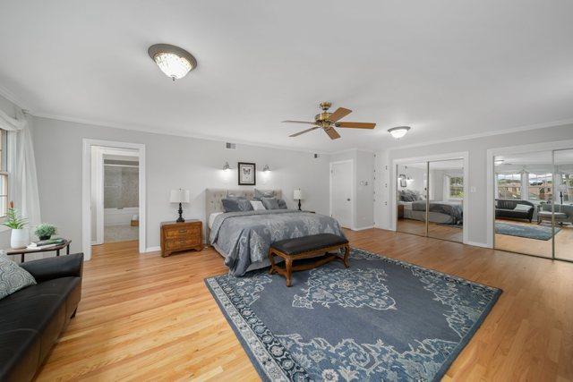 bedroom with ornamental molding, multiple closets, and wood finished floors