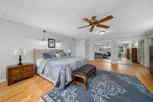 bedroom with visible vents, crown molding, a ceiling fan, and wood finished floors