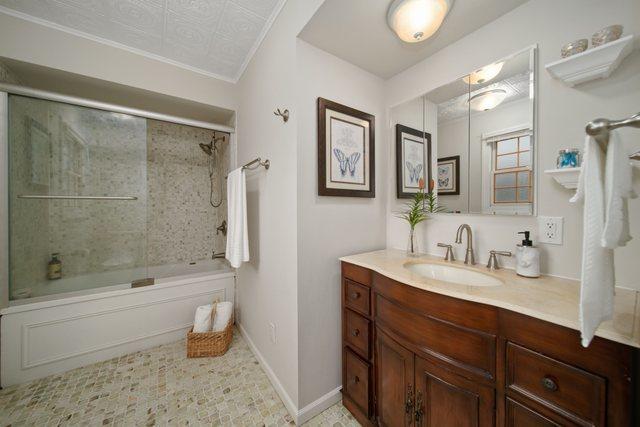 bathroom featuring combined bath / shower with glass door, baseboards, vanity, and crown molding