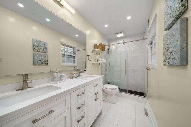 bathroom featuring a sink, toilet, a shower stall, and double vanity