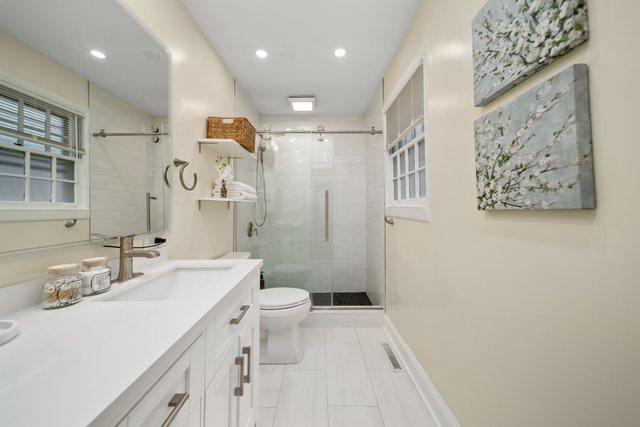 full bath with visible vents, toilet, a shower stall, baseboards, and vanity