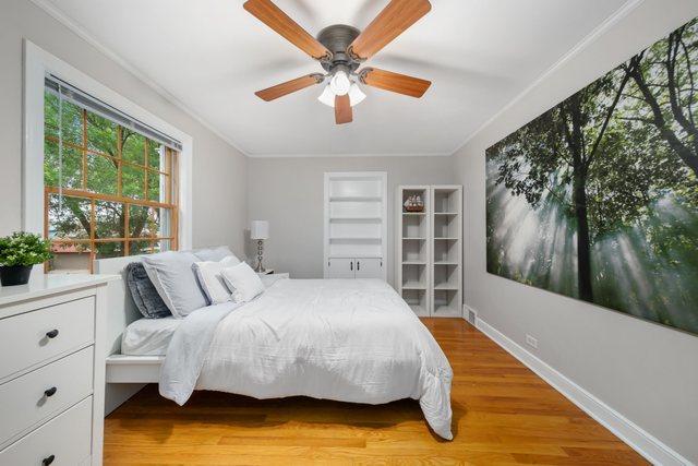 bedroom featuring light wood finished floors, crown molding, and baseboards